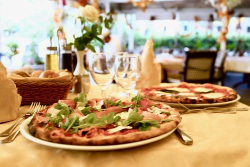 two pizzas on plates on a table with wine glasses at Hotel Victoria in Lugano