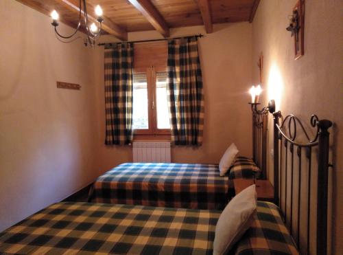 a bedroom with two beds and a window at Casa Rural El Tejo in Arroyo Frio