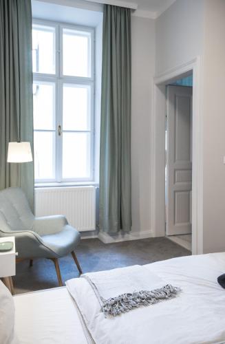a bedroom with a bed and a chair and a window at EL GUSTO HOMES Park in Sopron