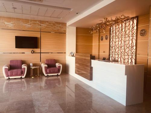 a lobby with two chairs and a counter and a tv at Season Inn Hotel in Barka