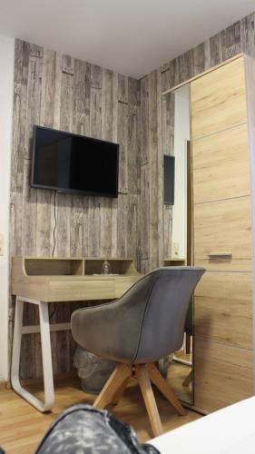 a living room with a desk and a television on a wall at Hotel Glas Schwarzwald in Fluorn