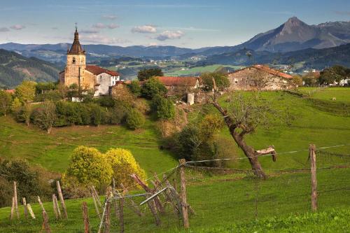 a village on a hill with a church in a field at ATeRIAN MUSKARIA in Zarautz