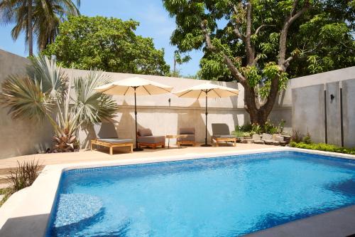 uma piscina com cadeiras e guarda-sóis num quintal em Villavela Hotel Boutique em Sonsonate