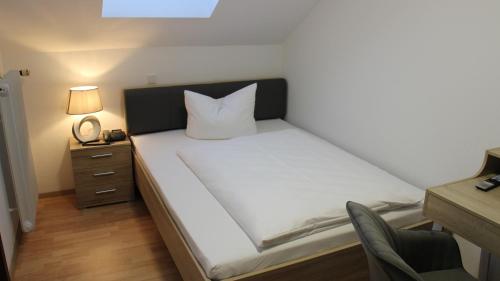 a bedroom with a white bed with a black headboard at Hotel Glas Schwarzwald in Fluorn