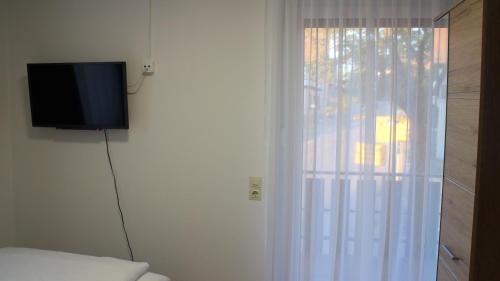 a room with a television and a bed with a window at Hotel Glas Schwarzwald in Fluorn