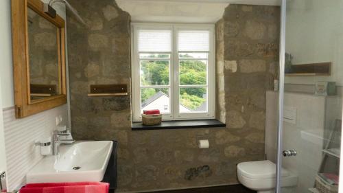 a bathroom with a sink and a toilet and a window at Ferienhaus Alte Schule in Volkesfeld