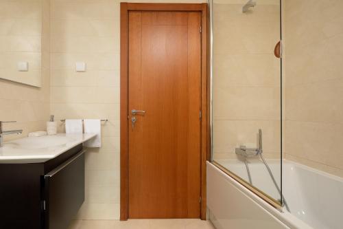 un bagno con doccia, lavandino e porta in legno di CASA DO MASSAPEZ, HOUSE B - LUXURY, PRIVATE POOL ad Arco da Calheta