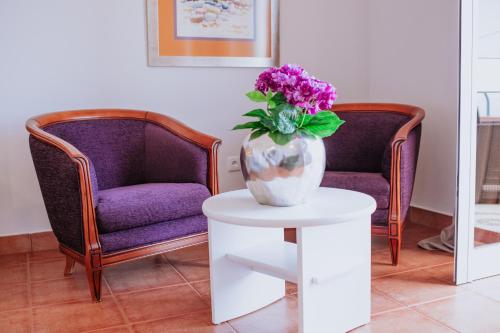 a vase of flowers sitting on a table next to two chairs at Villa Amore Accommodation in Paul do Mar