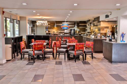 a dining room with red chairs and tables in a restaurant at Baymont by Wyndham Murfreesboro in Murfreesboro