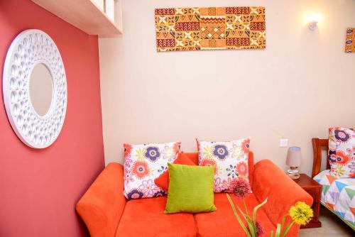 - un salon avec un canapé orange et des oreillers colorés dans l'établissement PIT-STOP NAIROBI: LOCATED NEAR AIRPORT & TOURIST CIRCUIT, à Nairobi