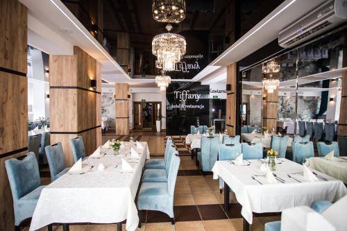 Hotel Tiffany في نوفي مياستو لوبافسكي: غرفة طعام مع طاولات بيضاء وكراسي زرقاء