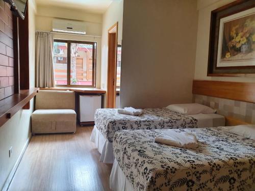 a hotel room with two beds and a chair at Pousada Sonho Meu Foz in Foz do Iguaçu