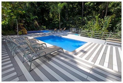 a deck with chairs and a swimming pool at Hotel Plaza Yara in Manuel Antonio