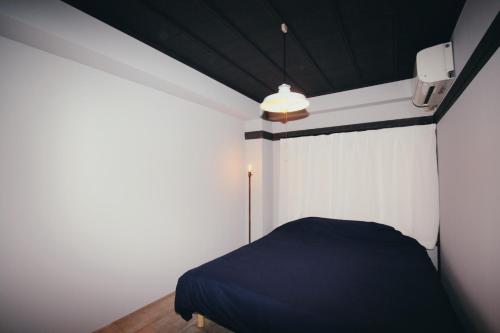 - une chambre avec un lit bleu et un mur blanc dans l'établissement Beppu hostel&cafe ourschestra -Vacation STAY 45089, à Beppu
