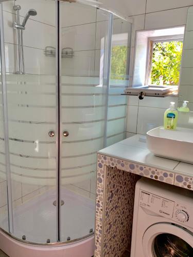 a glass shower in a bathroom with a washing machine at Villa Maximus in Hersonissos