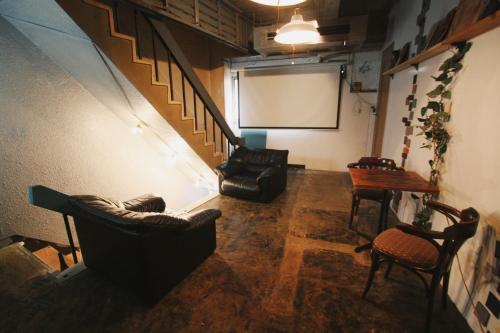 um quarto com duas cadeiras e um ecrã num quarto em Beppu hostel&cafe ourschestra - Vacation STAY 45098 em Beppu