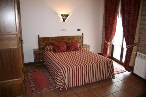 1 dormitorio con 1 cama grande con almohadas rojas en Hotel Rural La Enoteca del Marques, en Fermoselle