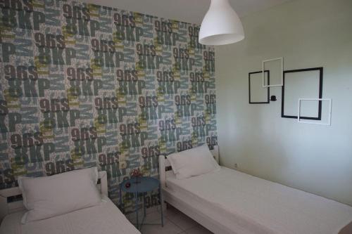 a room with two beds and a wall with a wallpaper at Christinas garden in Patra