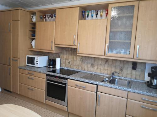 a kitchen with wooden cabinets and a sink and a microwave at Ferienhaus Lang in Nordenham