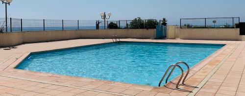 une grande piscine d'eau bleue sur une terrasse dans l'établissement Le Zéphyr, superbe appartement à la Corniche avec parking, à Sète