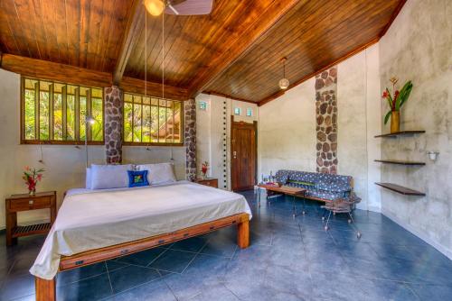 a bedroom with a bed and a couch and windows at Omega Tours Eco-Jungle Lodge in La Ceiba