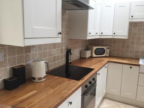 a kitchen with white cabinets and a counter top at The Coach House in Cardiff