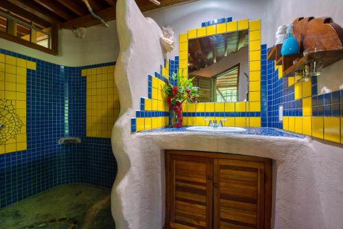 a bathroom with blue and yellow tiles and a sink at Omega Tours Eco-Jungle Lodge in La Ceiba