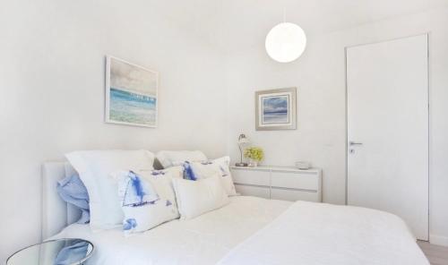 - une chambre blanche avec un lit blanc et des oreillers bleus dans l'établissement Apartament Sea Towers View, à Gdynia