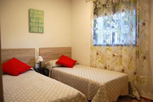 a bedroom with two beds with red pillows and a window at Casa de David in Córdoba