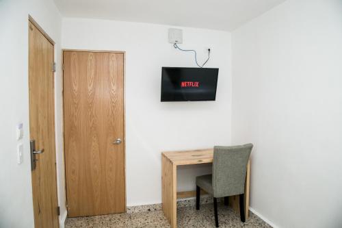 a small desk with a chair and a tv on a wall at Booking 500 in Monterrey