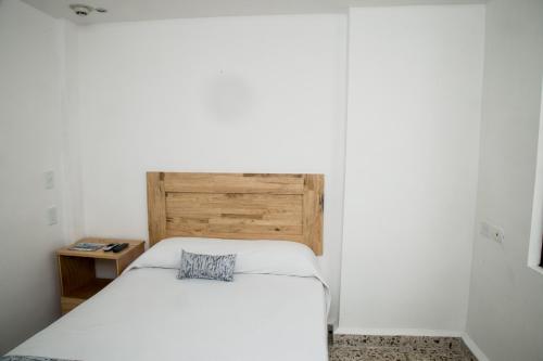 a bedroom with a white bed with a wooden headboard at Booking 500 in Monterrey