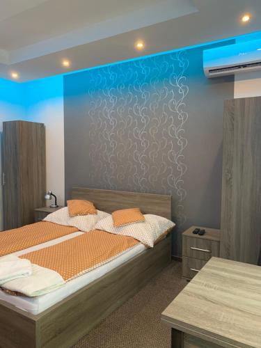 1 dormitorio con 2 camas y pared azul en Váci Vendégház, en Nyíregyháza