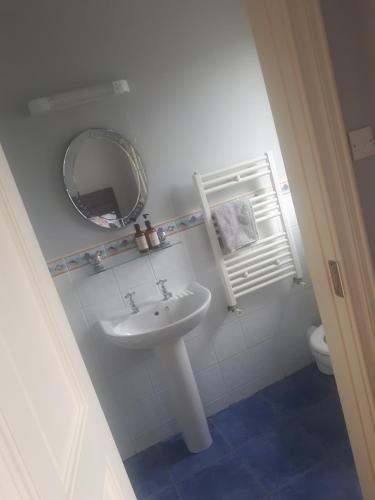 a white bathroom with a sink and a mirror at Carriglea in Listowel