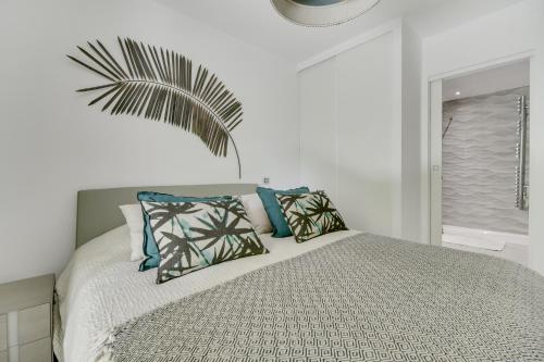 ein Schlafzimmer mit einem Bett mit Kissen und einer Palme in der Unterkunft Luxury & Exclusive Resort in Saint-Tropez