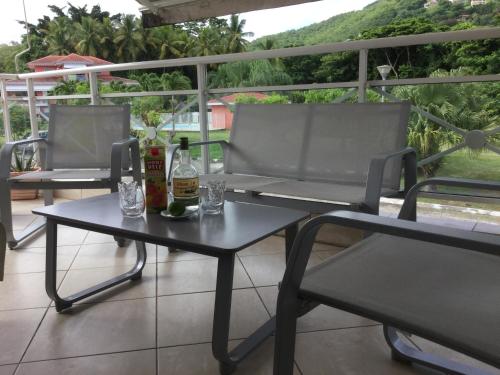 two chairs and a table with two bottles of alcohol at DOUC IRMA in Les Trois-Îlets