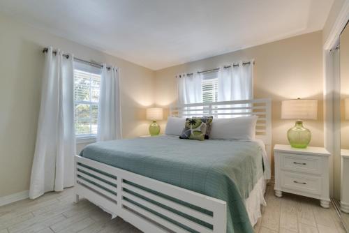 a bedroom with a white bed and two windows at Buttonwood Cottage in Siesta Key