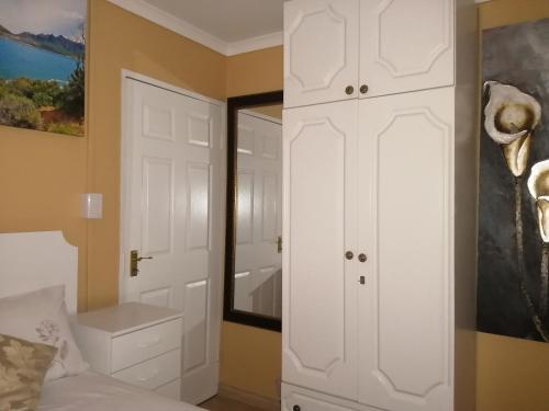 1 dormitorio con armario blanco y espejo en Onyx on Sycamore, en Ciudad del Cabo