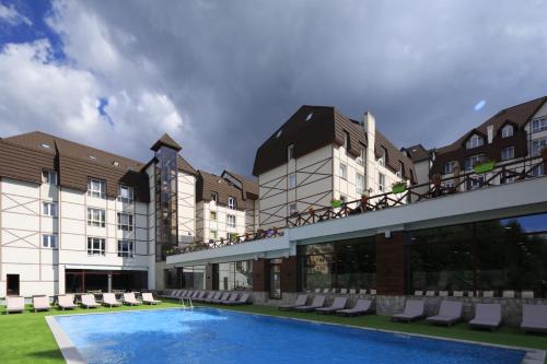 a hotel with a swimming pool in front of a building at Apartment Planinska Carolija in Kopaonik
