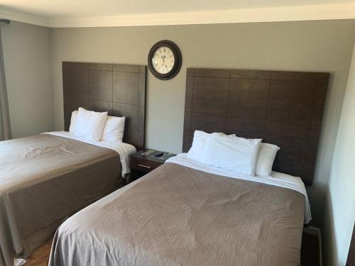 two beds in a hotel room with a clock on the wall at Mountain Trail Lodge and Vacation Rentals in Oakhurst