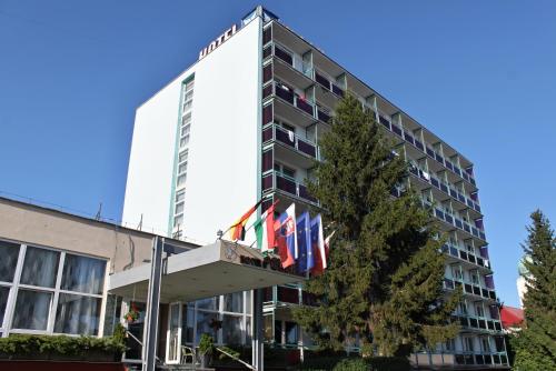 a hotel with flags in front of a building at Hotel Pelikán in Lučenec