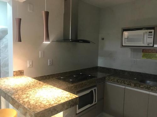 a kitchen with a counter top and a microwave at Paradise Temporada Cobertura 4 Quartos com Jacuzzi e Churrasqueira no Thermas Paradise - Rio Quente in Rio Quente