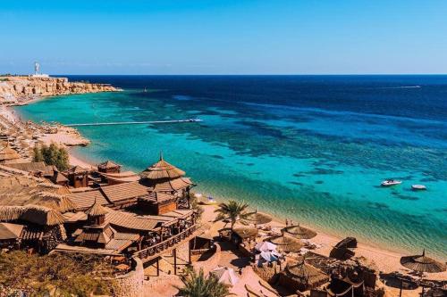 a beach with a group of umbrellas and the ocean at Sultan Sharm El Sheikh Hadaba Farsha in Sharm El Sheikh