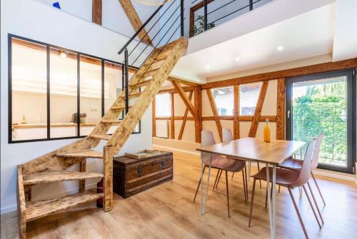 a dining room with a wooden table and a spiral staircase at La Chambre du 20 in Osthoffen