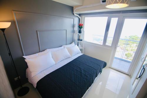 een slaapkamer met een bed met kussens en een raam bij Alexandrea Suite Taal View by Wind SMDC Tagaytay in Tagaytay