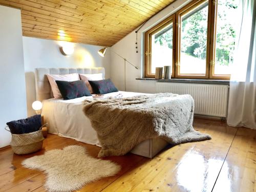 a bedroom with a bed with a blanket and windows at Sielanka w Brennej in Brenna
