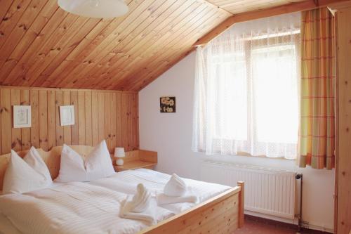 ゾンネンアルペ・ナスフェルトにあるMontanara Hausの木製の天井のベッドルーム(白い大型ベッド1台付)