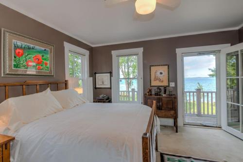 a bedroom with a large white bed and windows at The Spring Lighthouse B&B in Elk Rapids