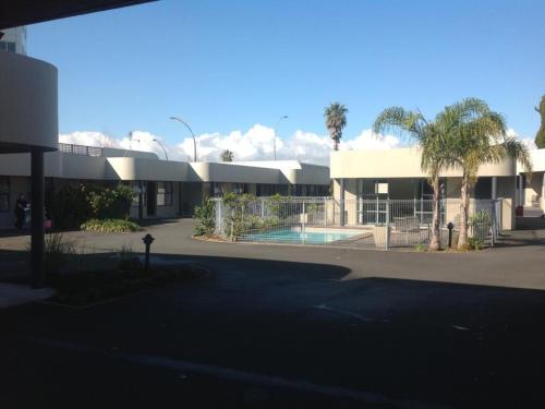 a building with a swimming pool in front of it at Durham Court Motor Inn in Tauranga