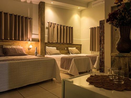 a hotel room with two beds and a table at Pousada Villa Real in Areia