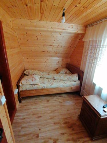 a room with a bed in a wooden cabin at Pensiunea Poarta Lui Ionele in Gîrda de Sus